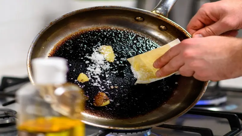 Aplicando una capa fina de aceite con papel de cocina en una sartén de acero hasta que se vuelve negra.
