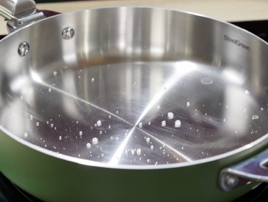 Sartén de acero inoxidable con la técnica de la gota de agua formando una bola perfecta